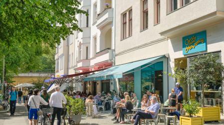 Außengastronomie in einer Gewerbestraße mit vielen Menschen auf den Plätzen